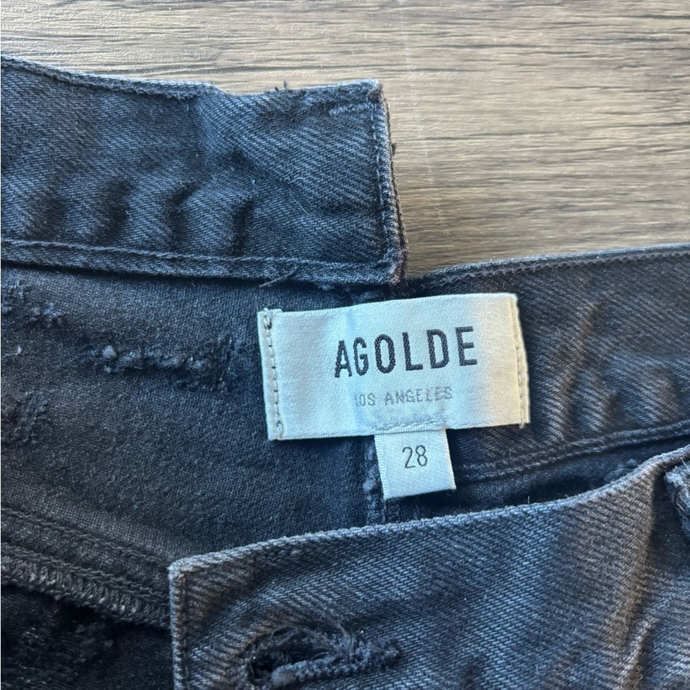 Agolde feverish woman’s black cross over distressed straight leg jeans.